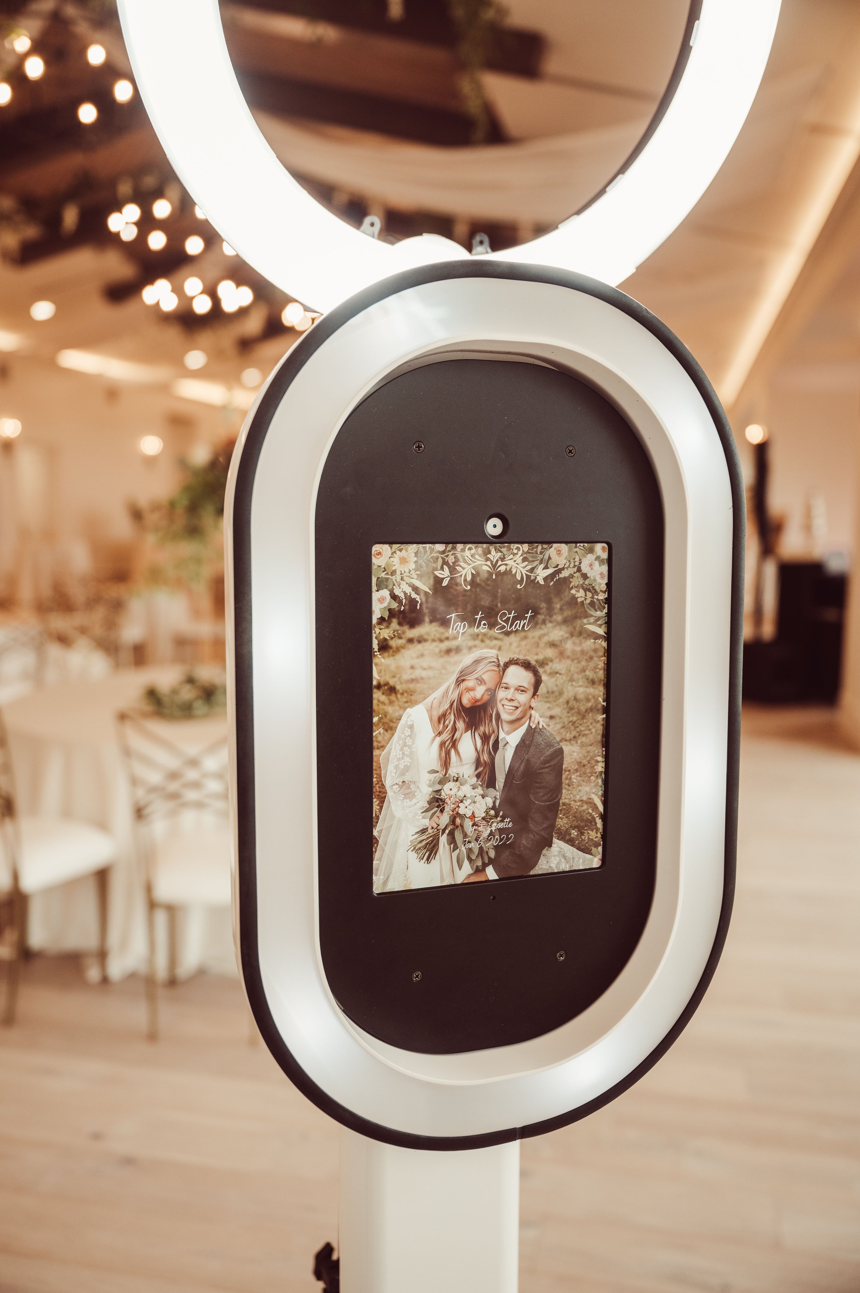Our studio photo booth with its ring light, set up against a white floral wall