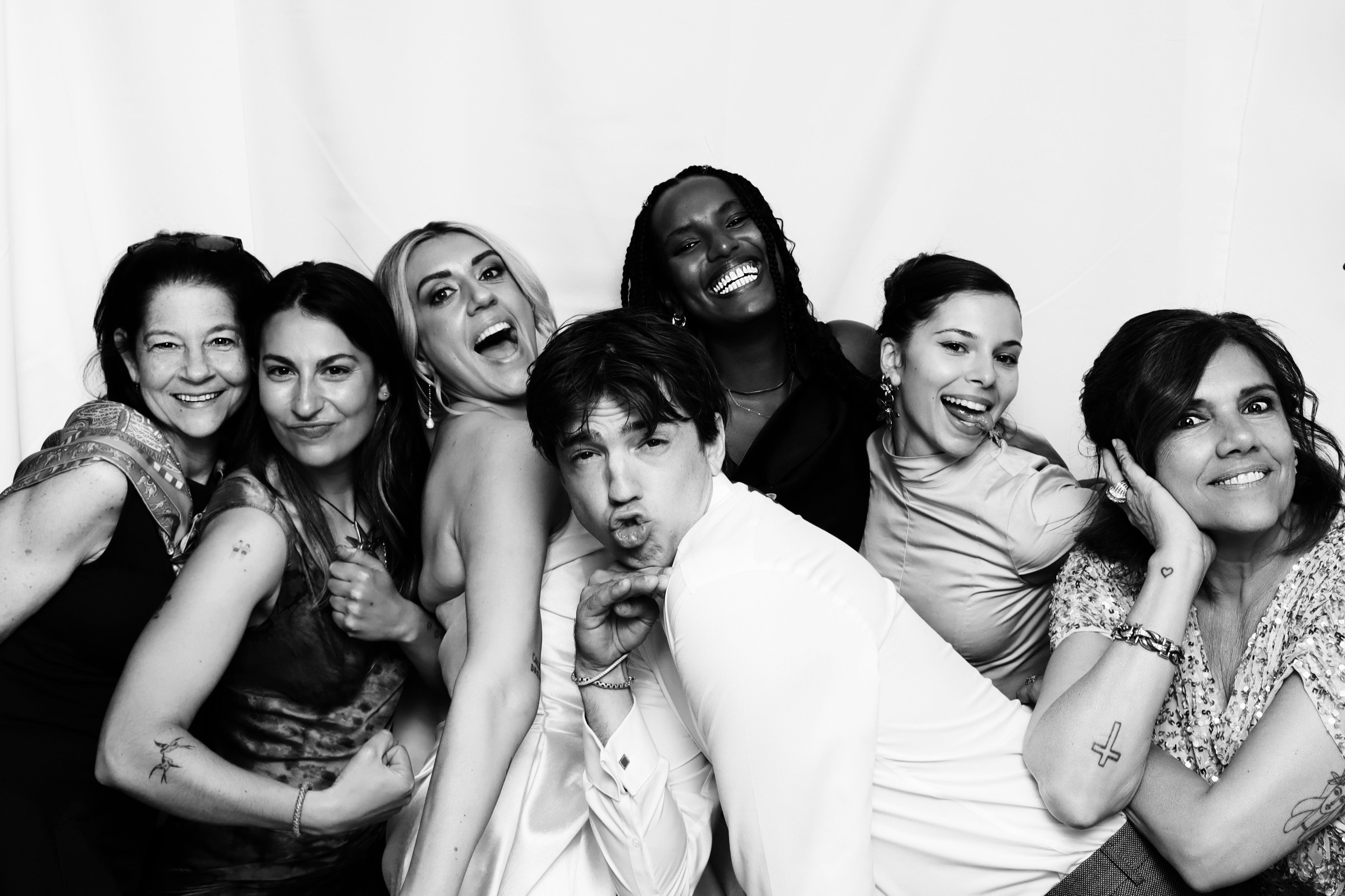 A group of friends posing together in black and white on a white backdrop