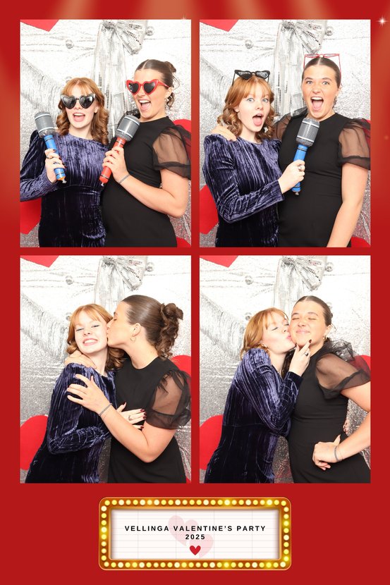 Four-frame photo booth print of two women with toy microphones and heart sunglasses on a red Valentine's layout